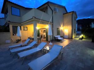 a group of lounge chairs and umbrellas on a patio at Ferienhaus Sommerflucht 2 in Barbat na Rabu