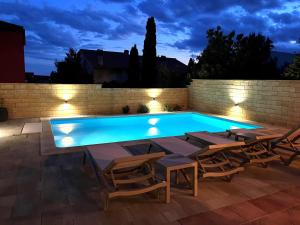 a swimming pool with tables and chairs next to a brick wall at Ferienhaus Sommerflucht 2 in Barbat na Rabu