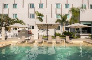 a pool with chairs and umbrellas in front of a building at Holiday Inn Express Tapachula by IHG in Tapachula