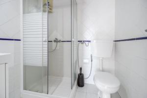 a white bathroom with a shower and a toilet at Saude Beach House in Costa da Caparica