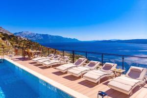 a pool with lounge chairs and a view of the water at Villa Mia Mit Pool, Whirlpool, Fitnessraum, Sauna in Lokva Rogoznica
