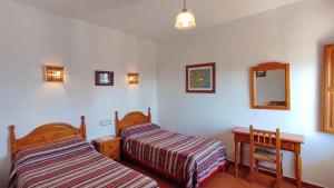 a bedroom with two beds and a table and a mirror at Casa Número 5 in Válor