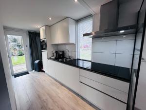 a kitchen with white cabinets and a black counter top at Bungalowpark Simpelveld - Delta 125 in Simpelveld