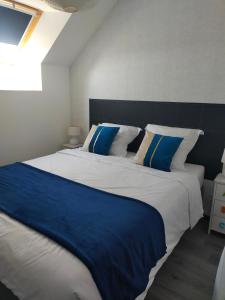 a bedroom with a large bed with blue and white pillows at Le gîte d'Isa in Montfarville