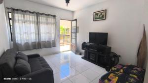 ein Wohnzimmer mit Sofa und Fernseher in der Unterkunft Bertioga pé na areia in Bertioga
