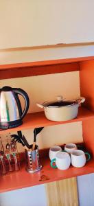 a shelf with pots and pans and cups on it at Reigns home in Eldoret +35 photos