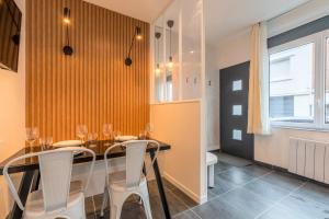 a dining room with a glass table and white chairs at Maison 2 chambres proche du tram, parking gratuit in La Madeleine
