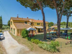 una casa amarilla con un patio de juegos delante de ella en Il Pino - appartamento Ciliegio, en Cecina