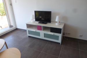 a white entertainment center with a flat screen tv on it at Les Marines du Soleil à Saint-Florent in Patrimonio