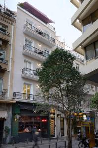 a tall white building with a tree in front of it at AthenSun Luxury Suites in Athens