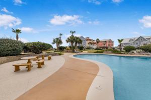 ein Schwimmbad mit Bänken neben einem Resort in der Unterkunft GS Plantation West 1339 by Vacation Homes Collection in Gulf Highlands