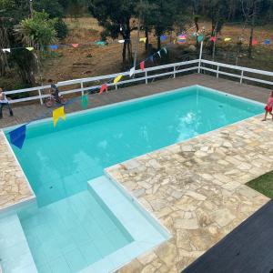 a swimming pool with blue water in a yard at Chalé 1 in Nova Friburgo