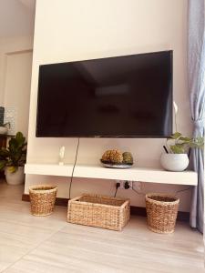 a flat screen tv on a wall with baskets at Unit One by Hideout Lounge in Kandy