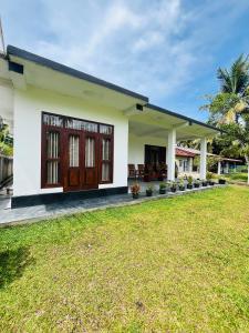 a house with a lawn in front of it at Hikka Garden Villa in Hikkaduwa