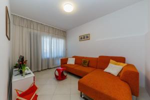 ein Wohnzimmer mit einem orangenen Sofa in einem Zimmer in der Unterkunft Ferienhaus in Ražanj mit Großem Garten in Ražanj + 32 Fotos