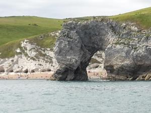 a group of people on a beach near a rock formation at HighTide - 2 bed with parking, balcony & sea view. in Swanage +37 photos
