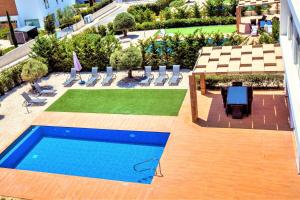 vista sul tetto di una piscina con sedie e prato di Luxuriöse Villa Mit Privatem Pool Und Whirlpool a Peyia