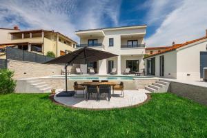 a backyard with a table and chairs and a pool at Villa Cascada in Muntić