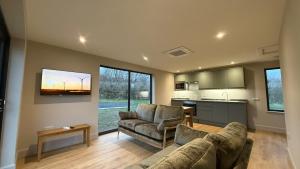 a living room with two couches and a kitchen at Caerketton View Lodges in Loanhead
