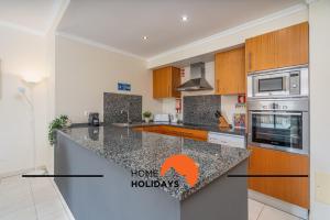 - une cuisine avec des comptoirs en granit et des placards en bois dans l'établissement #284 Vista das Ondas by Home Holidays, à Olhos de Água