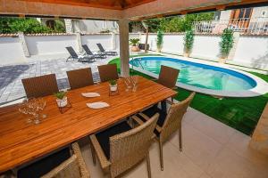 a wooden table and chairs next to a swimming pool at Villa Karla in Novalja