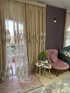 a living room with a pink chair and a window at Beverly Hills apartment in Sheikh Zayed