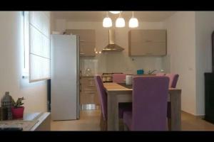 a kitchen with a table and purple chairs in a room at Family Holiday Home in Turanj
