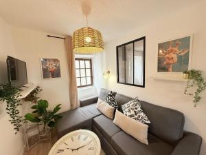 ein Wohnzimmer mit einem Sofa und einer Uhr in der Unterkunft Cosy Corail - T2 - Place Verdun in Pau