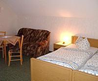 Zimmer mit einem Bett, einem Stuhl und einem Tisch in der Unterkunft Hotel-Pension Märkischheide in Vetschau