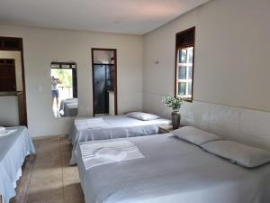 a room with three beds and a person taking a picture at Pousada Vila Verde in Juazeiro do Norte +4 photos