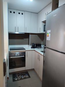 a kitchen with white cabinets and a stainless steel refrigerator at FRONT Rioja in Viña del Mar