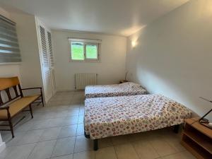 a bedroom with two beds and a chair and a window at Anglet Chiberta - Proche plage et golf in Anglet
