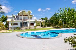 a villa with a swimming pool in front of a house at Northjoy Resort in Kilinochchi