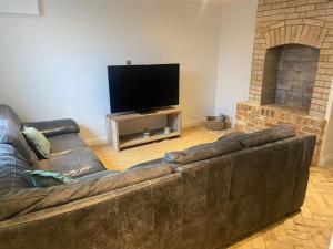 a living room with a leather couch and a flat screen tv at Number Forty One in Sudbury