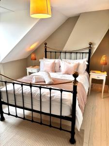 a bedroom with a black bed with white pillows at Seascape Luxury Cottage Southwold - Free Parking in Reydon