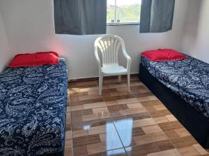 una stanza con due letti e una sedia di Casa Grande Barreiro Bh a Belo Horizonte