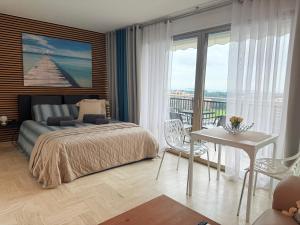 a bedroom with a bed and a table and a balcony at My Resid Appart Divina Cannes Marina vue mer in Mandelieu-la-Napoule