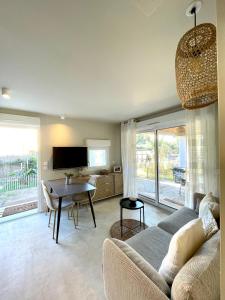 una sala de estar con un sofá y una mesa en Bas de villa la sablhyeres- 300m Plage de la Capte - 2 hébergements disponibles, en Hyères