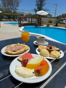a table with plates of food and fruit on it at Pousada Maresia Costa Azul in Rio das Ostras