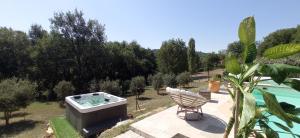 a garden with a hot tub and a chair on a patio at La Sousto Du Lac Sauvage in Esparron-de-Verdon