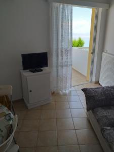 a living room with a flat screen tv on a cabinet at SereneLands Seaside House by MPS in Liyiá