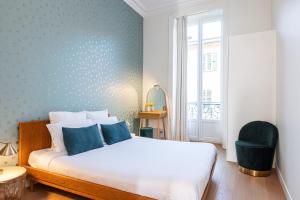 a bedroom with a white bed and a blue wall at REGINA - Somptueux 3 pièces - carré d'or Menton - vue mer in Menton
