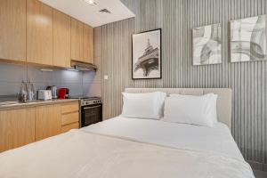 a bedroom with a white bed and a kitchen at Private Tropical Poolside Studio by Blue Cloud Holidays in Sharjah Intl