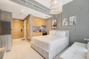 a bedroom with a large white bed and a kitchen at Private Tropical Poolside Studio by Blue Cloud Holidays in Sharjah Intl
