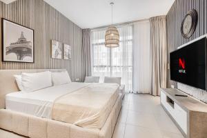 a bedroom with a bed and a flat screen tv at Private Tropical Poolside Studio by Blue Cloud Holidays in Sharjah Intl +17 photos