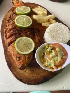 a plate of food with a fish and rice and lime slices at Hotel Casa Corleone in Garzón
