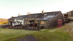 an old stone building with a red phone booth in front at Sunny Brow Cottage at Thompson Ground in Hawkshead