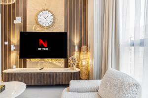 a living room with a tv and a clock on a wall at 1BR Wow Apartment in Sharjah - Crystal Retreat in Sharjah Intl