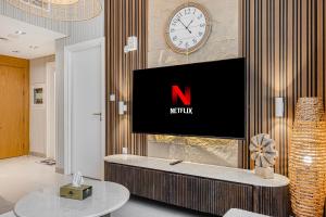 a living room with a television and a clock on the wall at 1BR Wow Apartment in Sharjah - Crystal Retreat in Sharjah Intl +23 photos