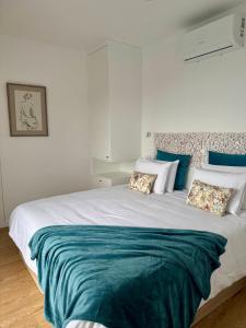 a bedroom with a large bed with blue and white pillows at Calheta Nest in Calheta
